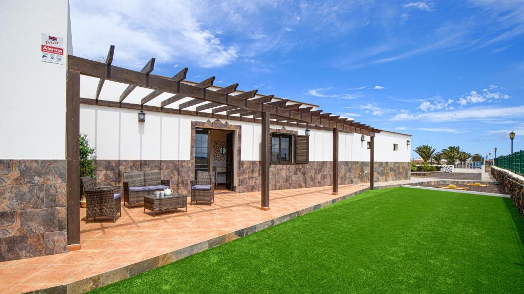 a patio with a green lawn in front of a building at Villa Elena in Lajares