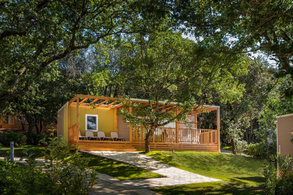 ein kleines Haus in einem Garten mit einer Veranda in der Unterkunft Maistra Camping Porto Sole Mobile homes in Vrsar