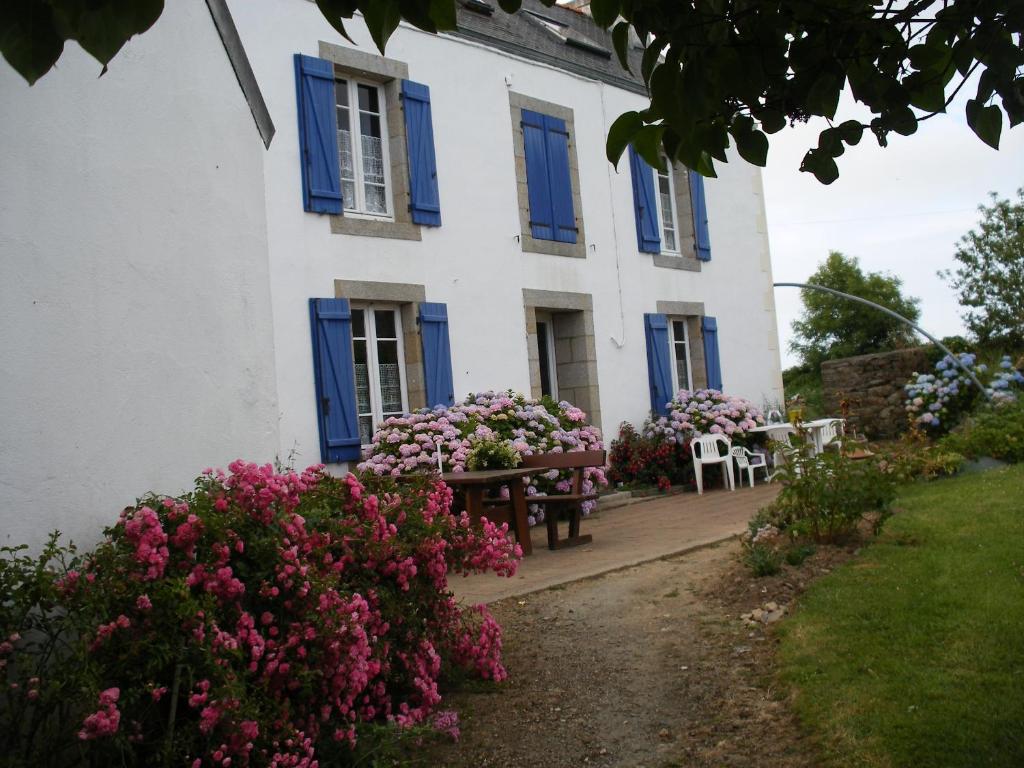 una casa con persianas azules y flores delante de ella en Les chambres d'hotes du cosquer, en Beuzec-Cap-Sizun