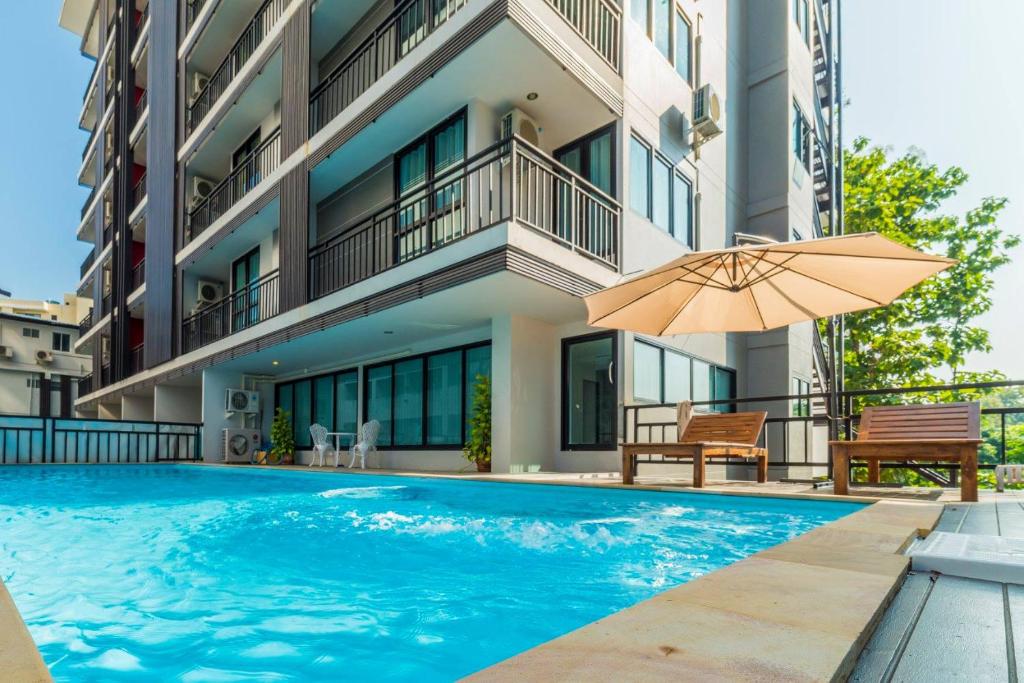 清邁的住宿－海可宮1號酒店，一座带遮阳伞的游泳池位于大楼旁