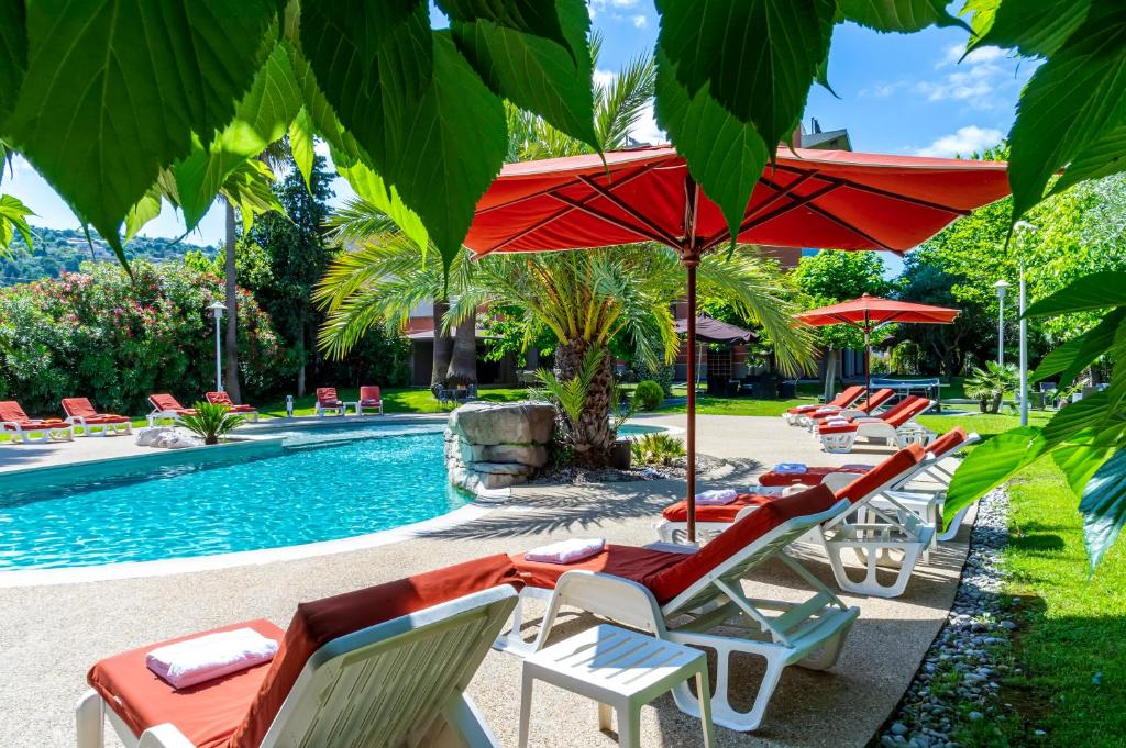 a group of chairs and umbrellas next to a pool at Servotel Saint-Vincent in Nice