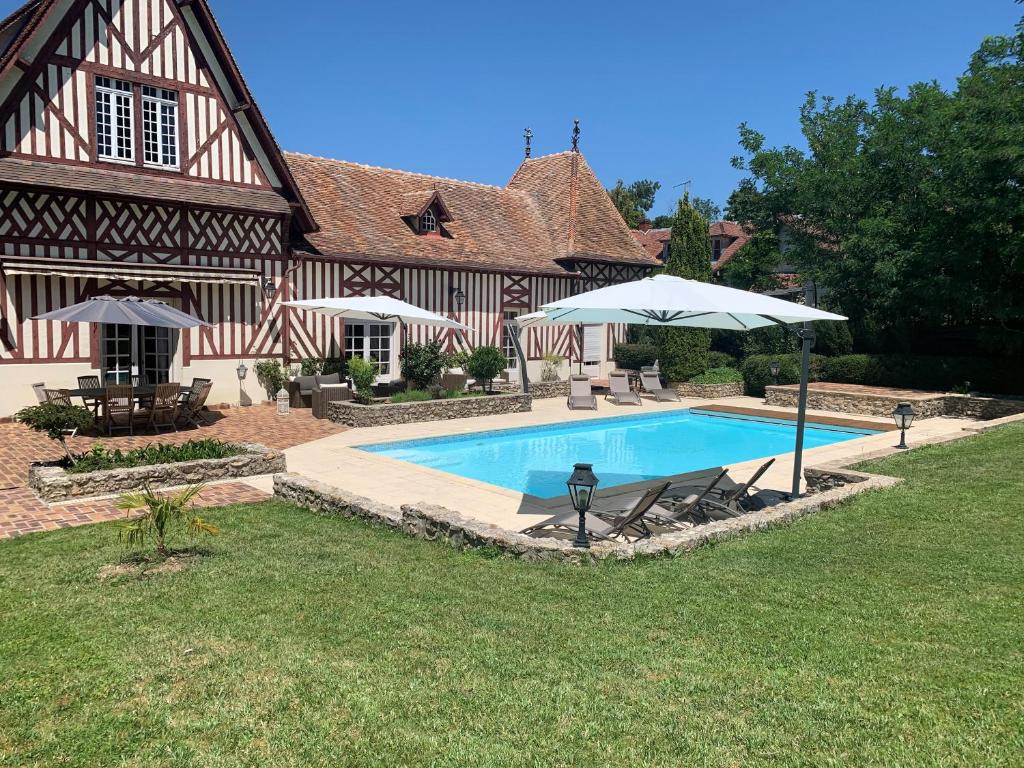 a house with a swimming pool and an umbrella at Marquise Barbot in Evry-Courcouronnes