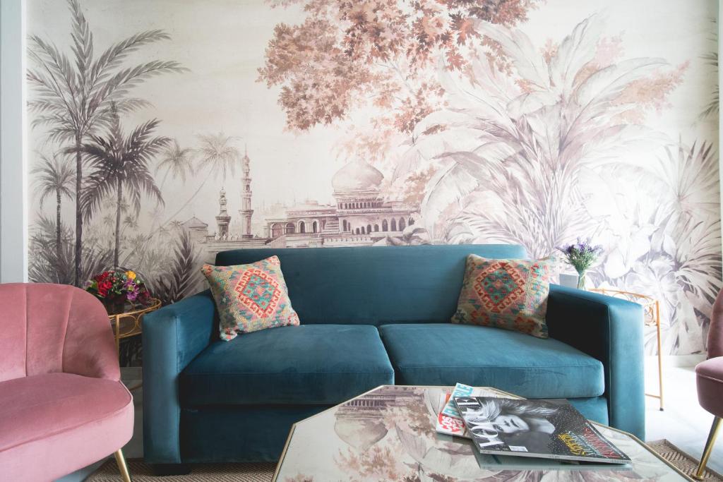 um sofá azul numa sala de estar com um mural de palma em Arco Macarena Suite em Sevilha