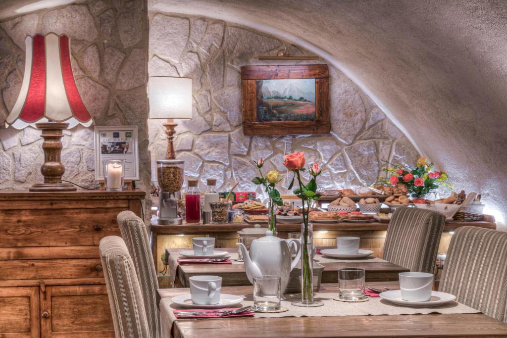 uma sala de jantar com uma mesa com cadeiras e uma parede de pedra em B&B Il Grottino Di Assergi em Assergi