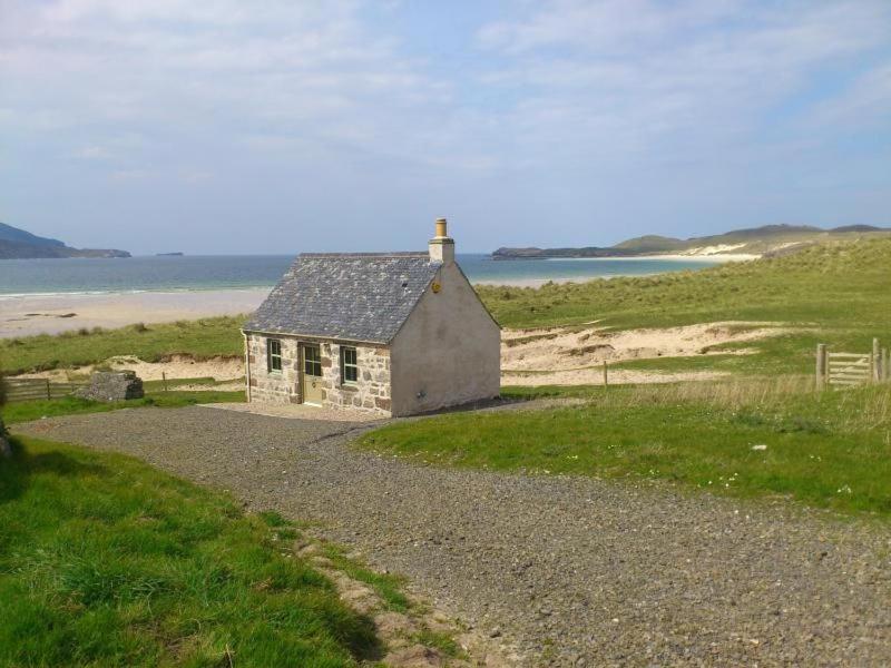 a small house sitting on the side of a beach at Balnakeil Beach Bothy in Durness