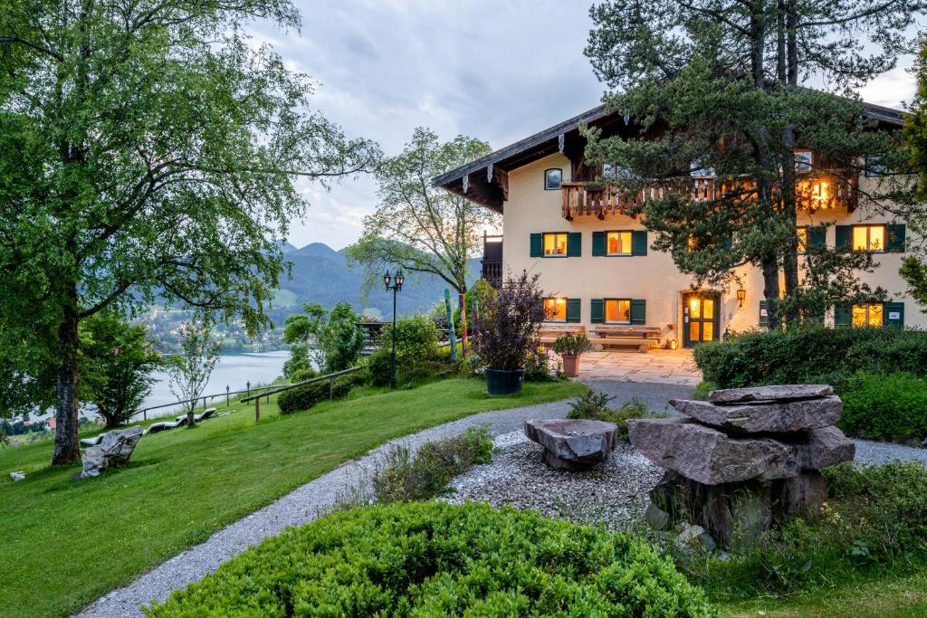a house with a garden in front of a lake at Der Westerhof Hotel in Tegernsee