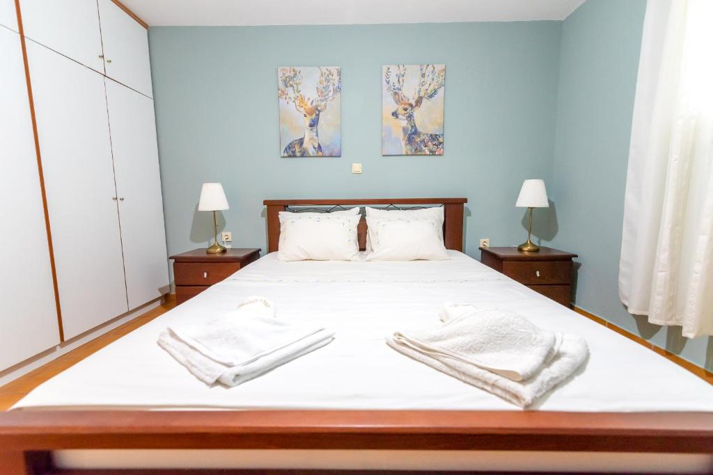 a bedroom with a large bed with white sheets at Pine trees apartment in Preveza