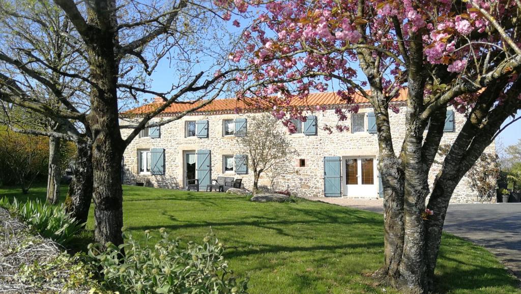 una gran casa de piedra con árboles delante de ella en 8 Le Chiron de la Roche 85130 Chanverrie, en La Verrie