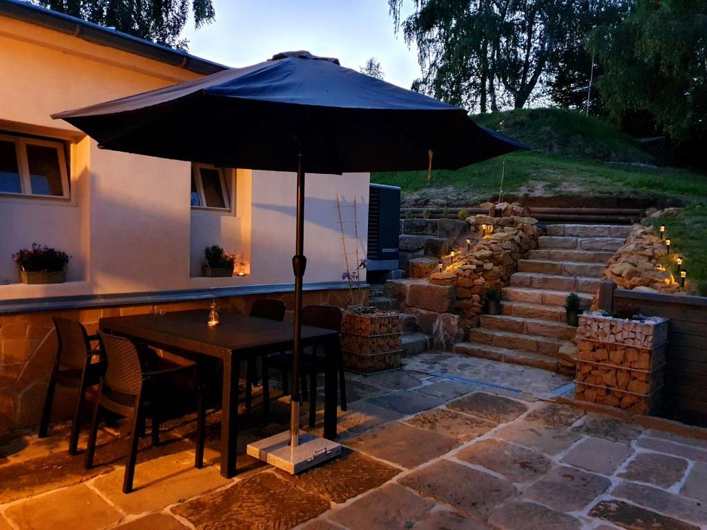 a table with an umbrella in front of a house at Hotel KORTUS in Jetřichovice