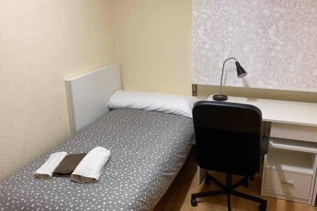 Schlafzimmer mit einem Bett, einem Schreibtisch und einem Stuhl in der Unterkunft Residencia 12 OCTUBRE in Madrid