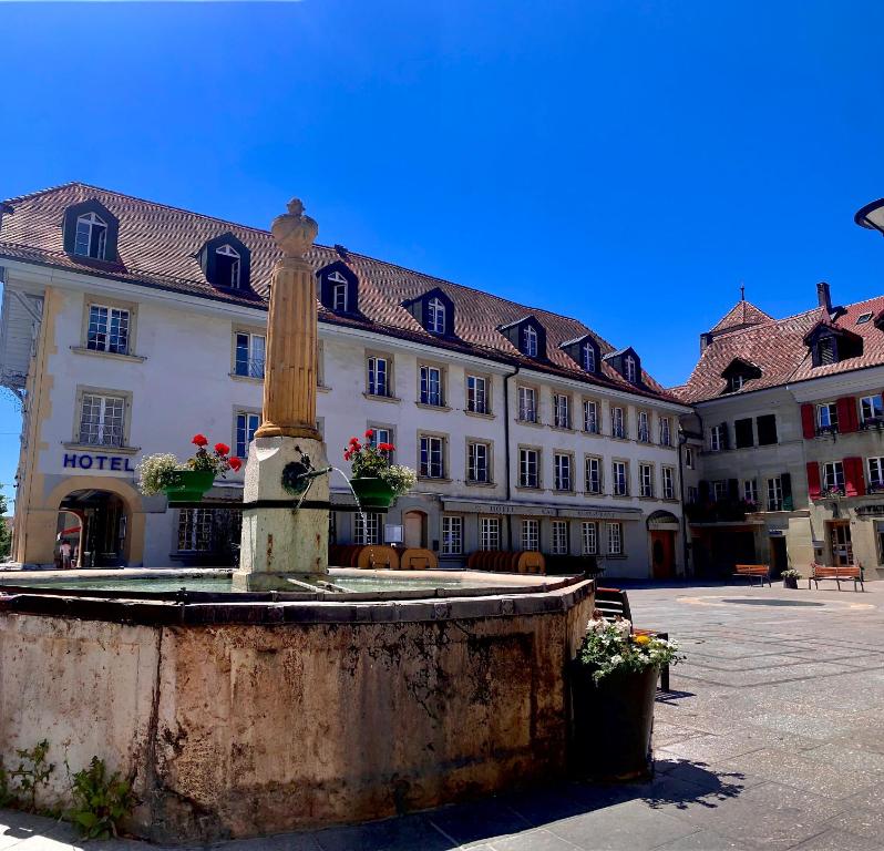 een fontein voor een groot gebouw bij SWISS HOTEL LA COURONNE in Avenches