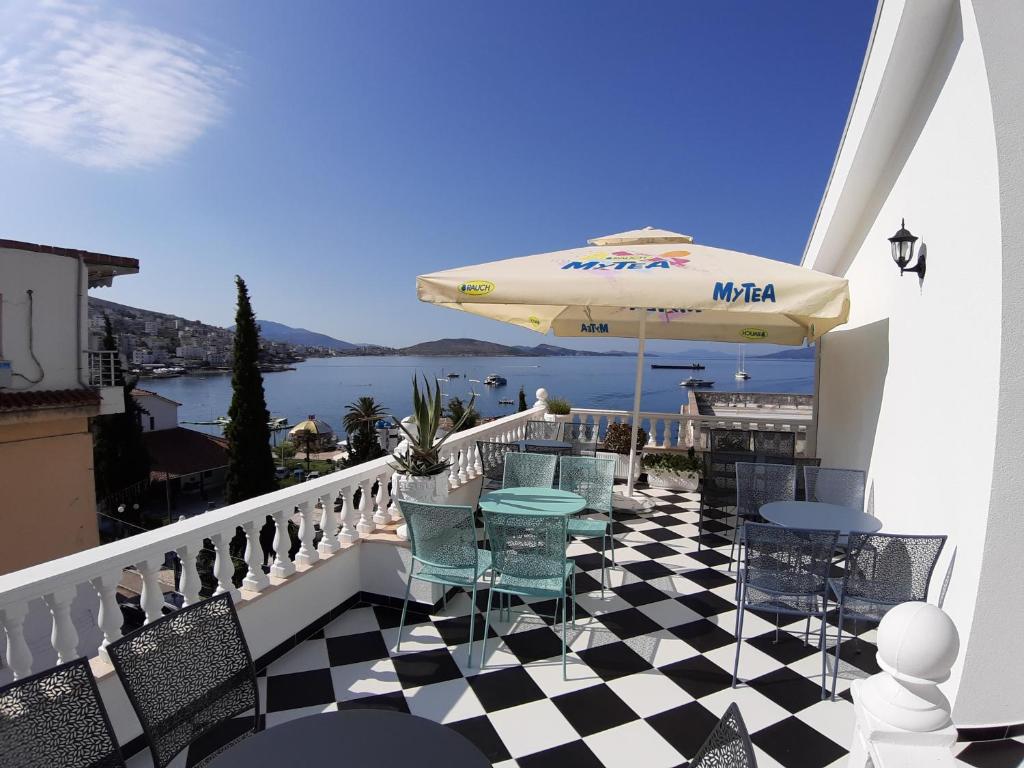 balcón con mesa, sillas y sombrilla en Bistrica Hotel, en Sarandë