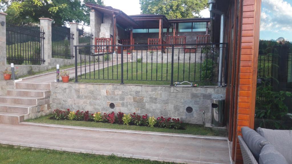 kamienna ściana z ogrodzeniem i kwiatami w obiekcie Lakata Guest House w mieście Zasele