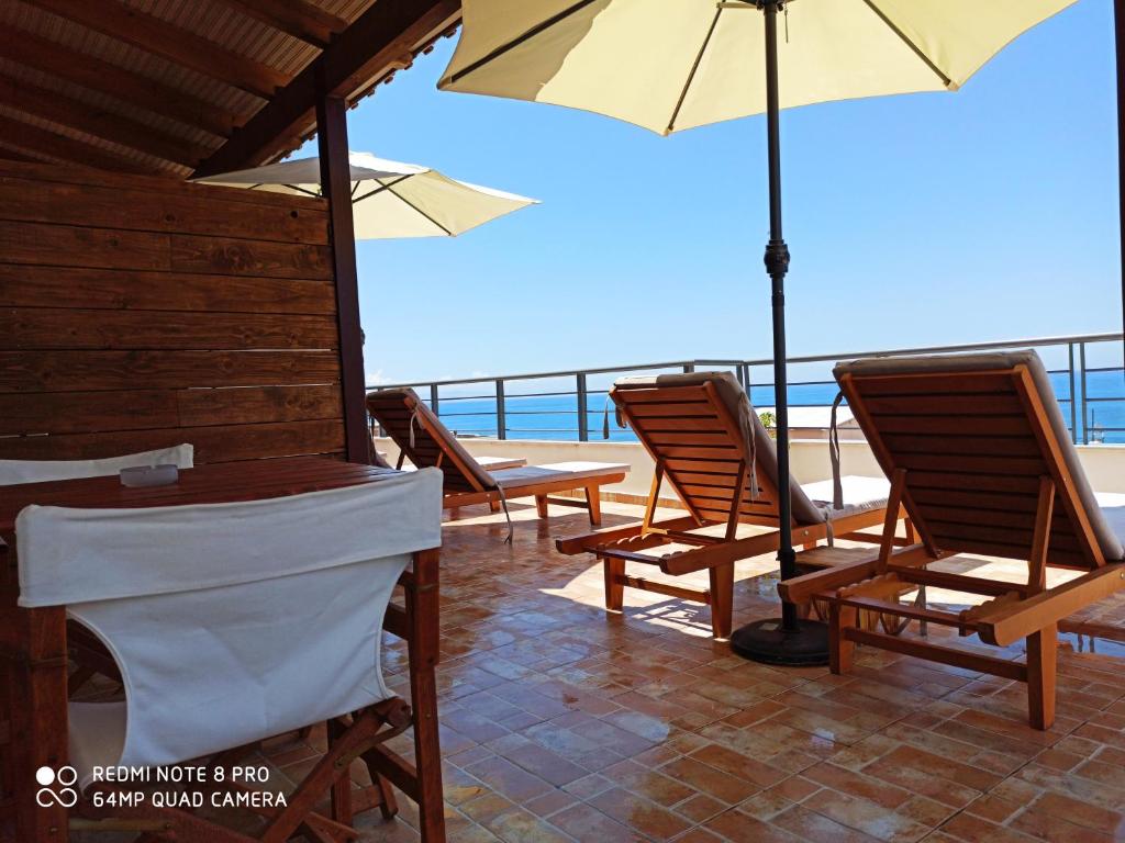 um grupo de cadeiras e guarda-sóis num pátio em Bourbos Summer Rooms em Himare