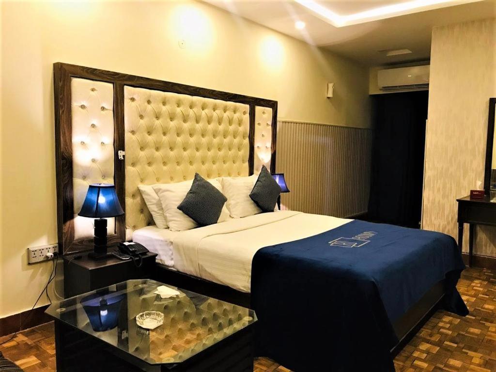 a bedroom with a large bed and a glass table at Atlas hotel in Islamabad