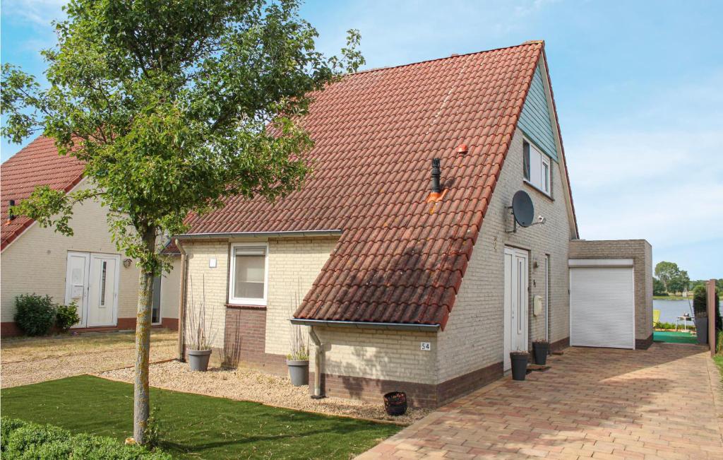 een huis met een rood dak en een boom bij Porta Isola - Villa Water in Stevensweert