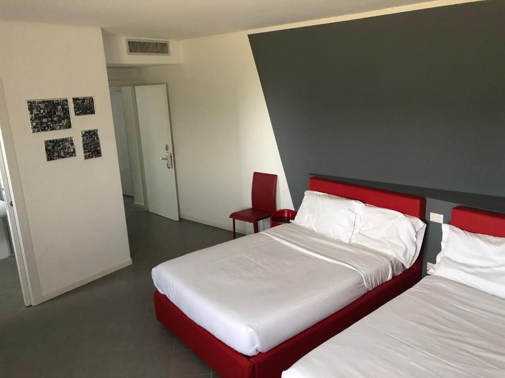 um quarto com 2 camas com lençóis vermelhos e brancos em Locanda Penaceto em Longare