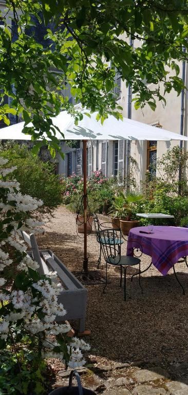 a table and chairs under a white umbrella at Le Ragois in Richelieu