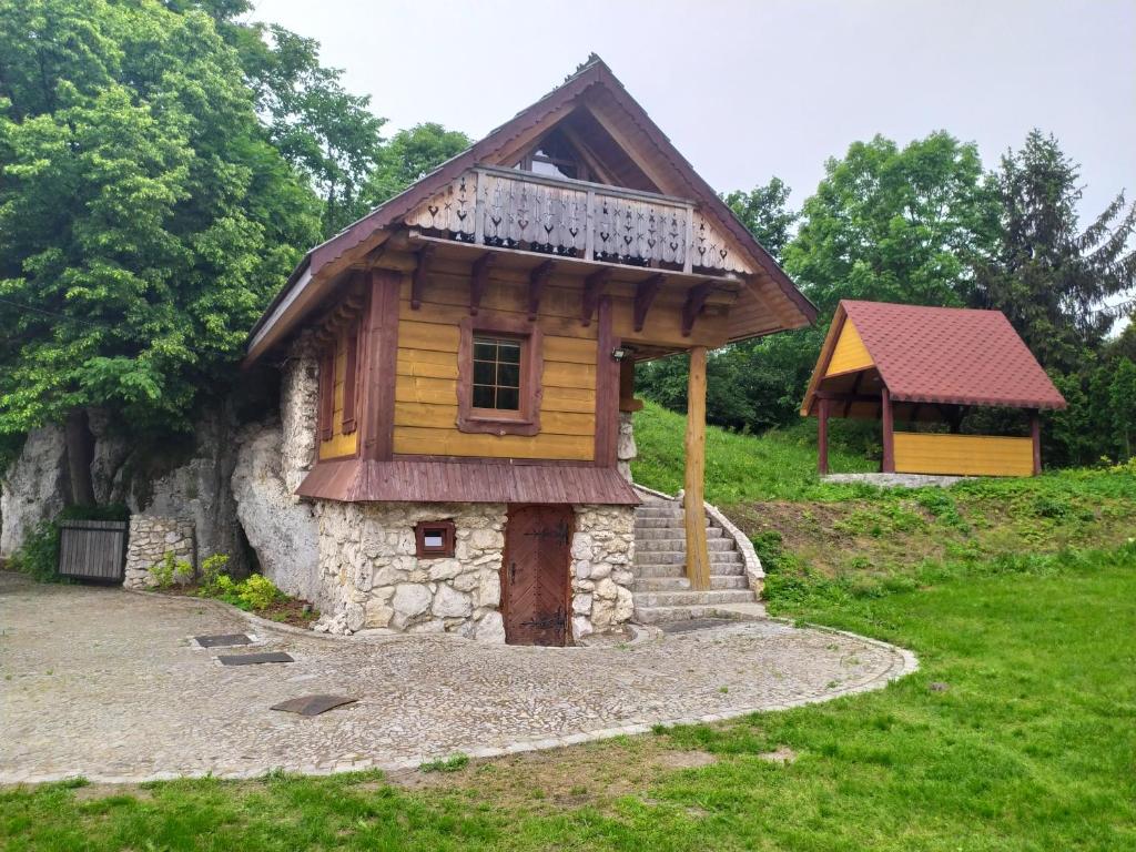 a small wooden house with a balcony on top at Domek w skale in Kroczyce