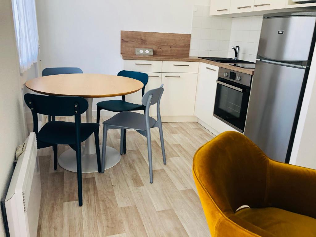 eine Küche mit Tisch und Stühlen und einem Kühlschrank in der Unterkunft Artimon Beach appart Les Sables d Olonne in Les Sables-dʼOlonne
