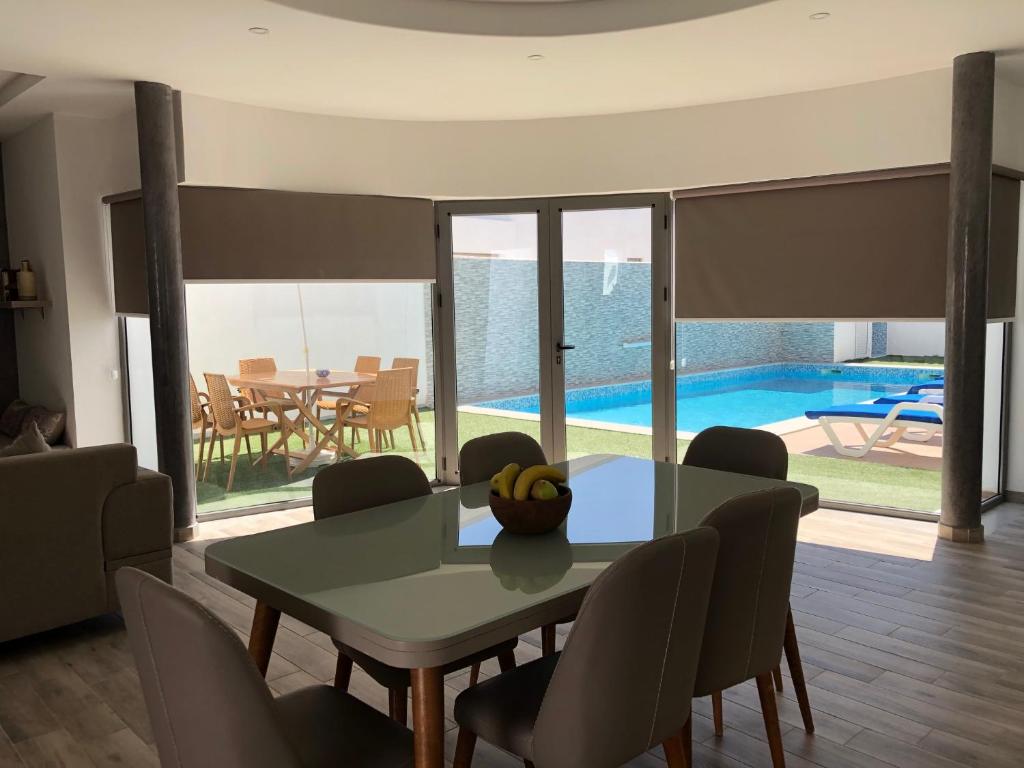 uma sala de jantar com mesa e cadeiras e uma piscina em VILLA ALOHA DJERBA plain pied haut de gamme piscine proche de la plage em Midoun