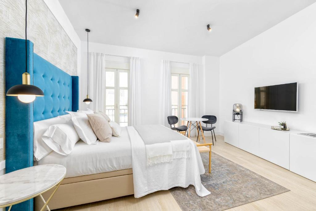 Dormitorio blanco y azul con cama y mesa en iloftmalaga Studio Apartments, en Málaga
