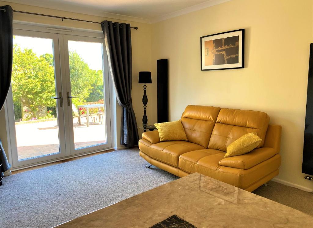 a living room with a couch and a sliding glass door at Luxury Suntrap in Private Complex St Leonards in Hastings