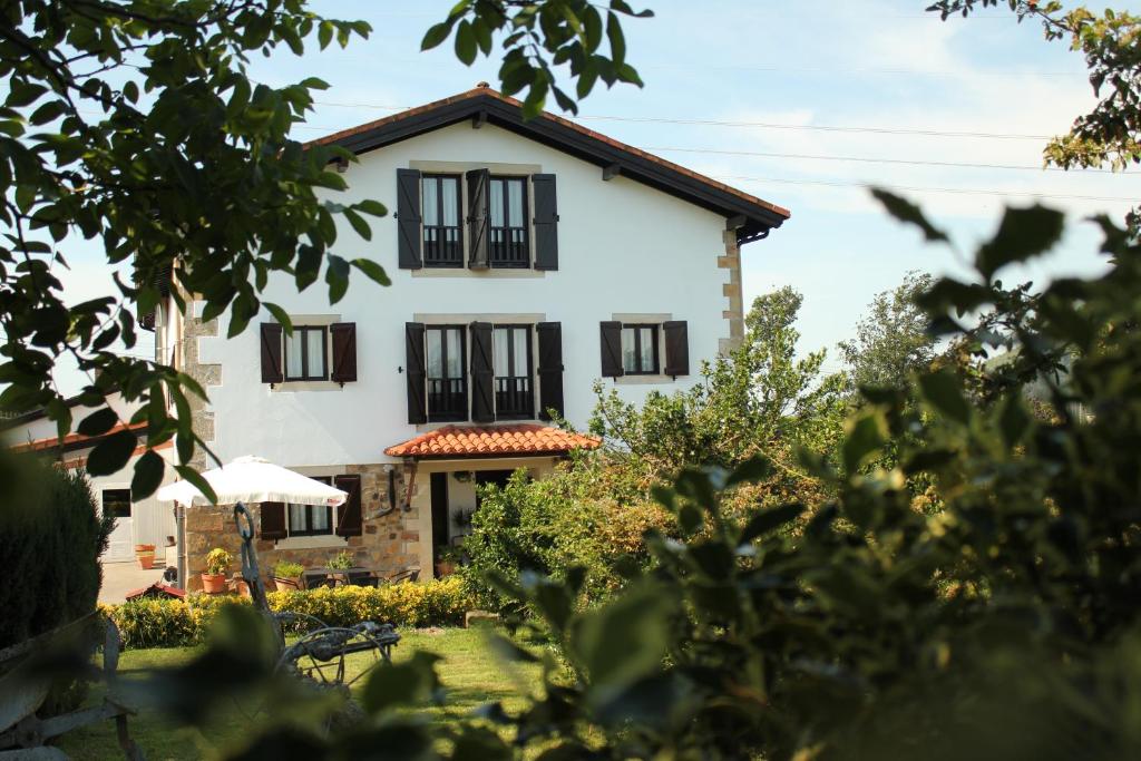 a white house with black windows at Astei Nekazalturismoa in Muxika