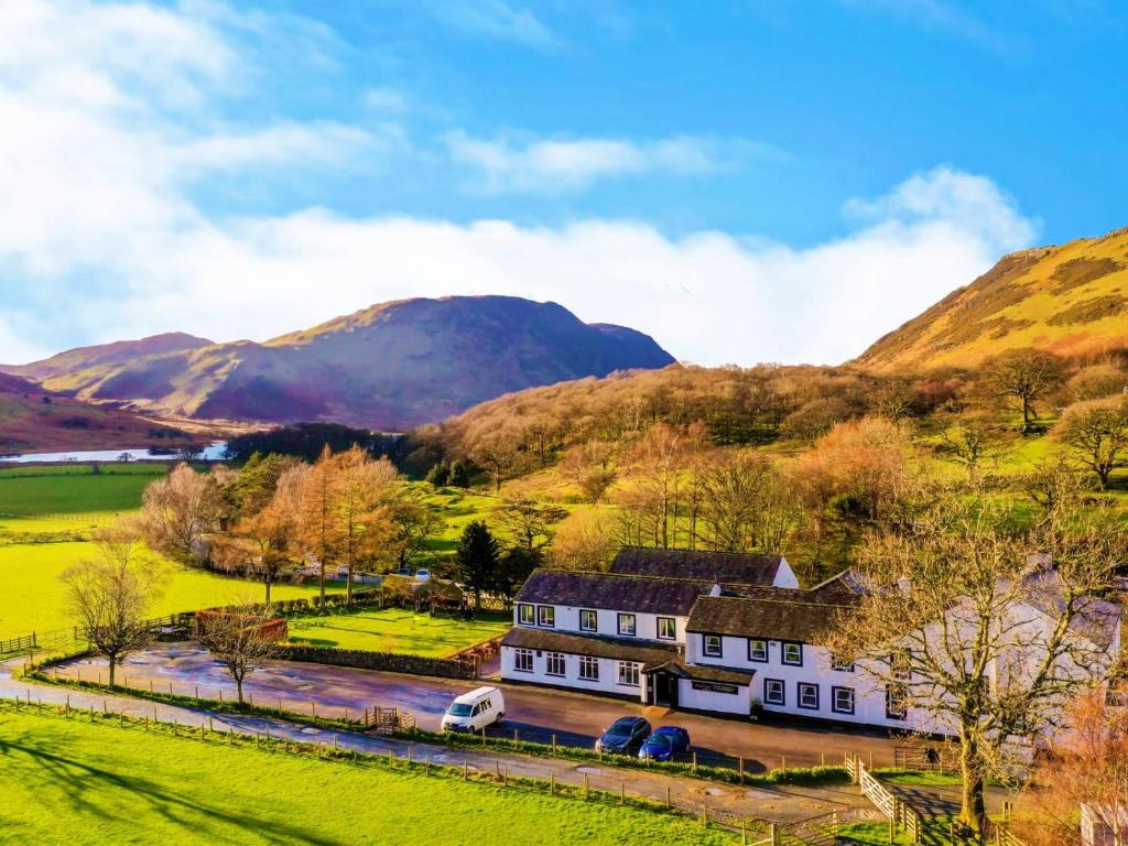 una casa en un campo con montañas en el fondo en Buttermere Court Hotel, en Buttermere