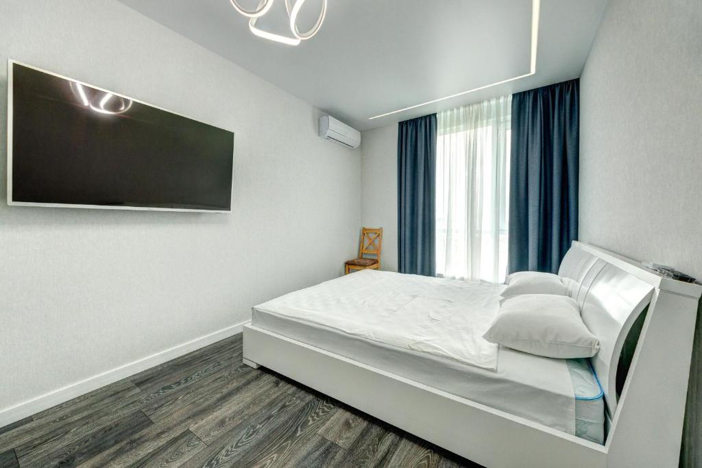 a bedroom with a bed and a flat screen tv at Apartment Voskresenska 18 , Парковые Озера in Kyiv