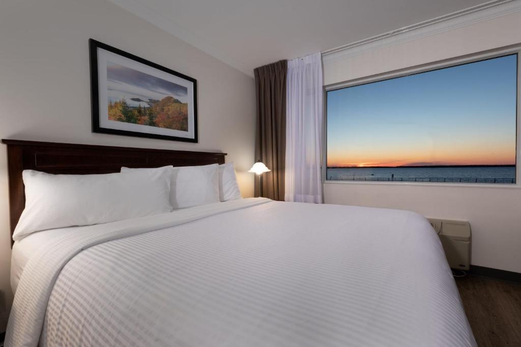 a bedroom with a large bed and a large window at Hotel Rimouski in Rimouski