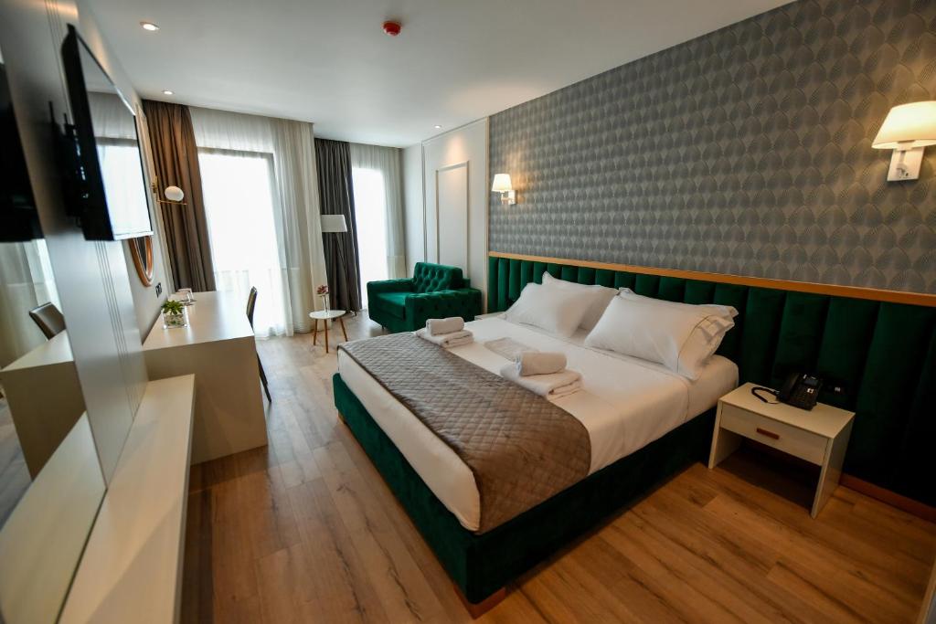 a bedroom with a large bed and a green wall at Iliad Hotel in Durrës
