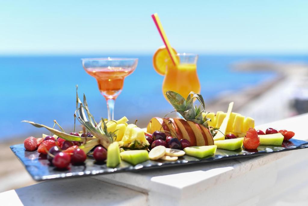 a plate of fruit on a table with a drink at Iliad Hotel in Durrës