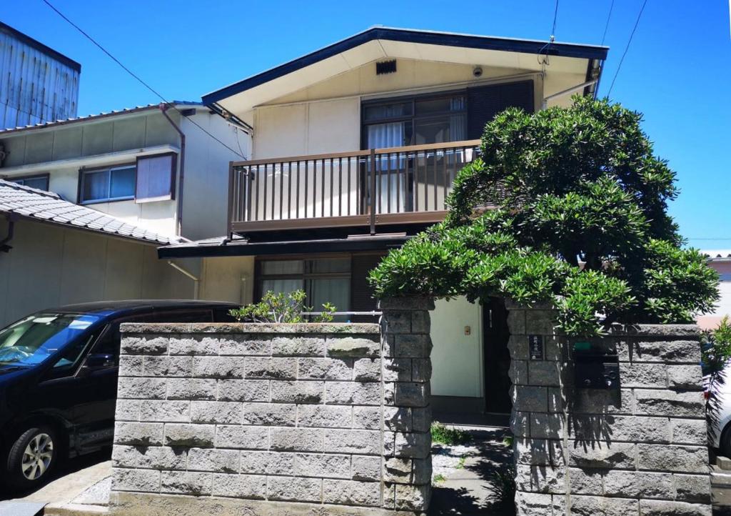 ein Haus mit einem Baum davor in der Unterkunft 浜町小院 Guest House in Takamatsu