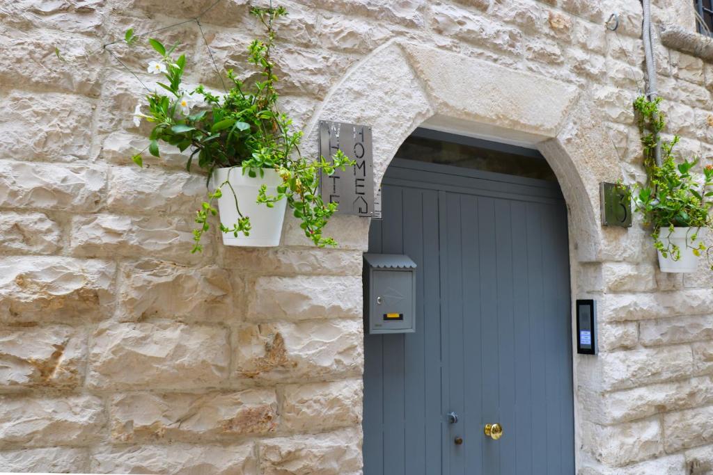un edificio de piedra con una puerta azul y macetas en White Home, en Bisceglie