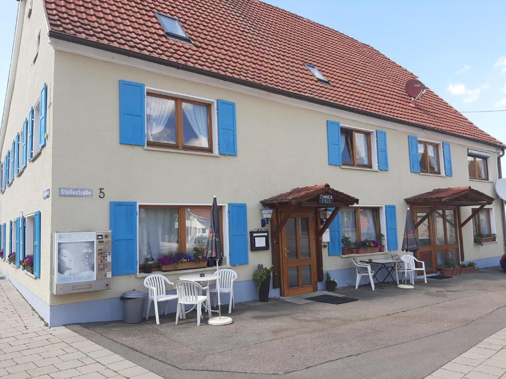 a building with blue windows and tables and chairs at Gästehaus Pension Waldhorn in Weilen unter den Rinnen