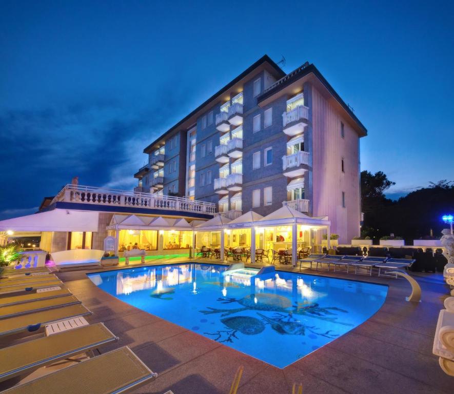 a hotel with a large swimming pool at night at Hotel Danieli in Caorle