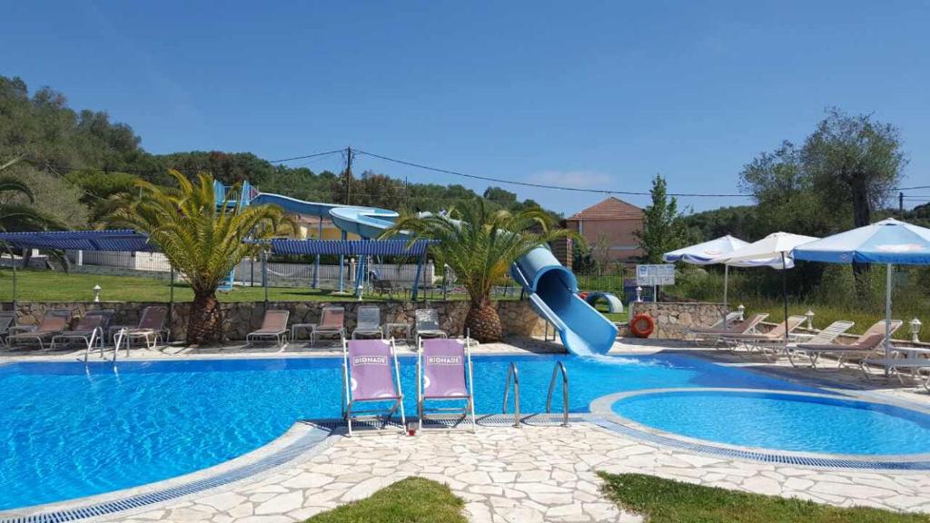 a swimming pool with a slide in a resort at Pension Nychterida in Marathias