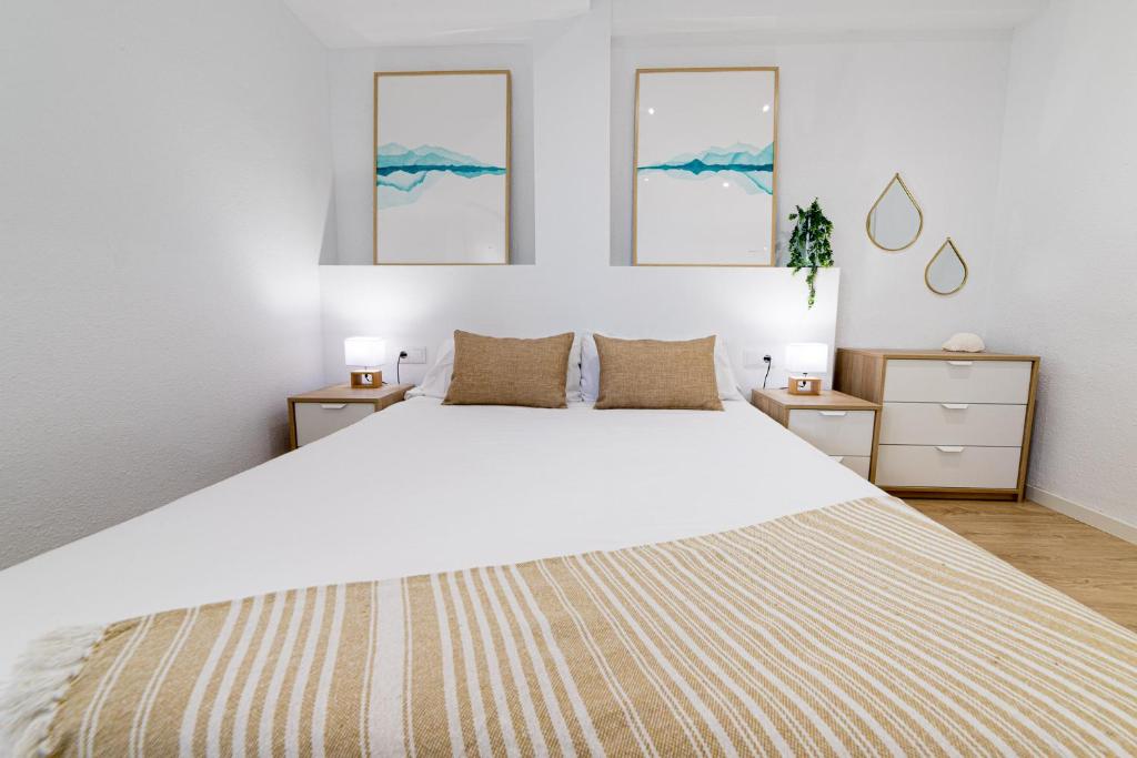 een slaapkamer met een groot wit bed met drie foto's aan de muur bij Moonkey - Apartamento Las Lanzas in El Campello