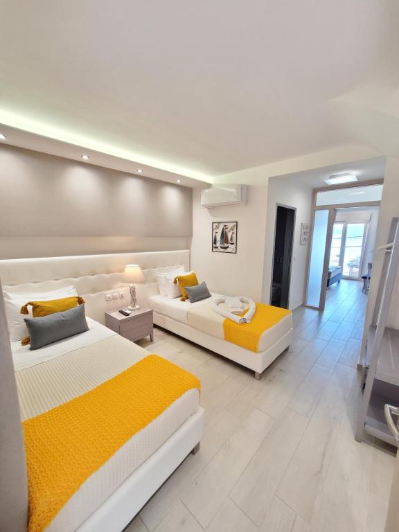 two beds in a large room with yellow and white at Deluxe Dina in Skala Potamias