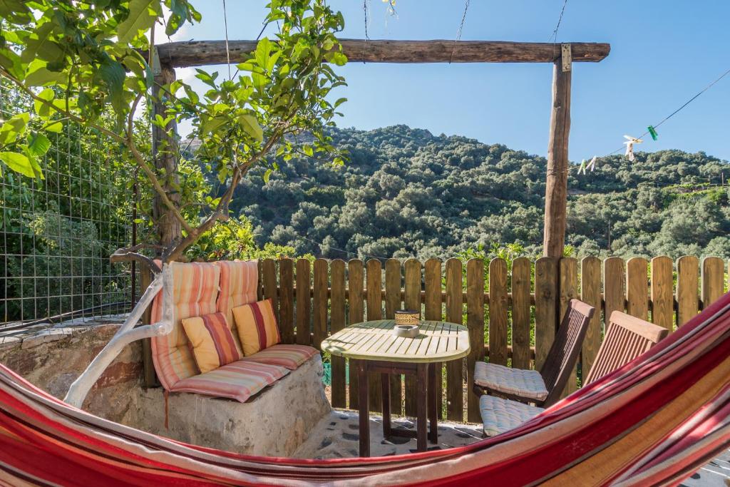 a hammock with a table and chairs in front of a fence at Spitia Katoi in Palaiochora