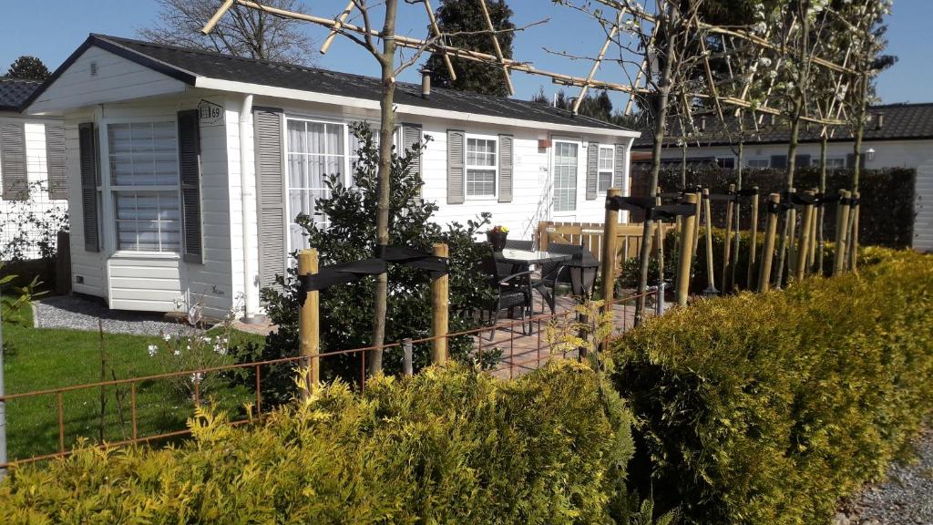 a white house with a fence in front of it at Bospareltjes Luxe chalets Alleen voor recreatie in Oisterwijk