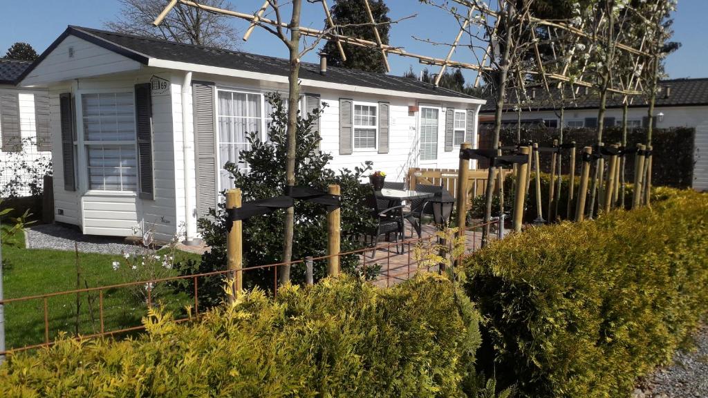 une maison blanche avec une clôture devant elle dans l'établissement Bospareltjes Luxe chalets Alleen voor recreatie, à Oisterwijk