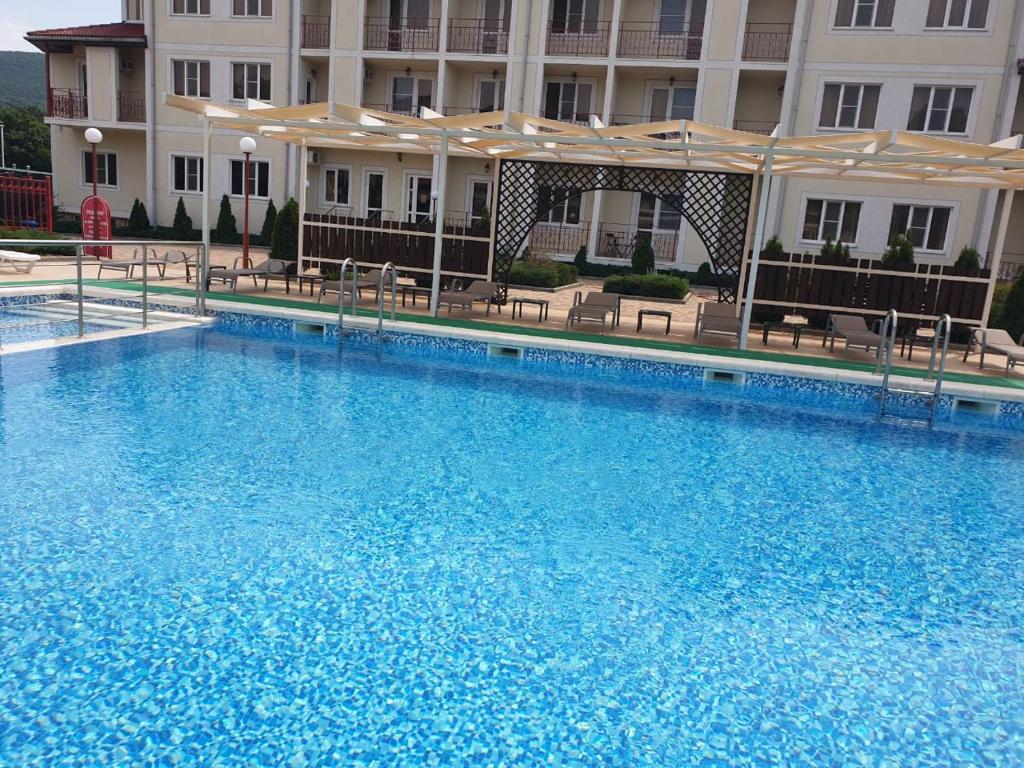 a large blue swimming pool in front of a building at Guest House Capri in Kabardinka