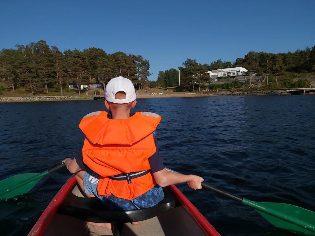 Un homme est assis dans un canoë sur l'eau dans l'établissement Cottage Langan, à Strömstad