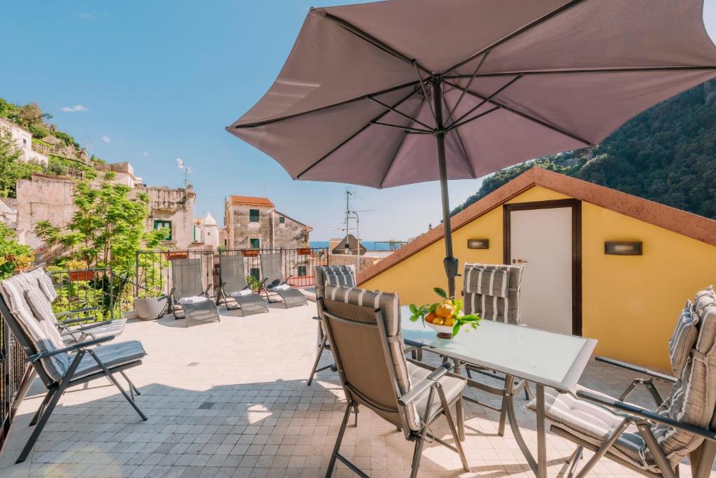 Bouganville Holiday house Amalfi في أمالفي: طاولة وكراسي مع مظلة على الفناء