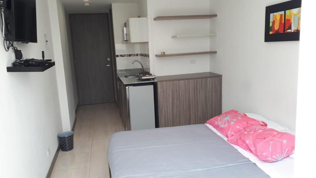 Habitación pequeña con cama y cocina en Apartaestudio Pereira, en Pereira