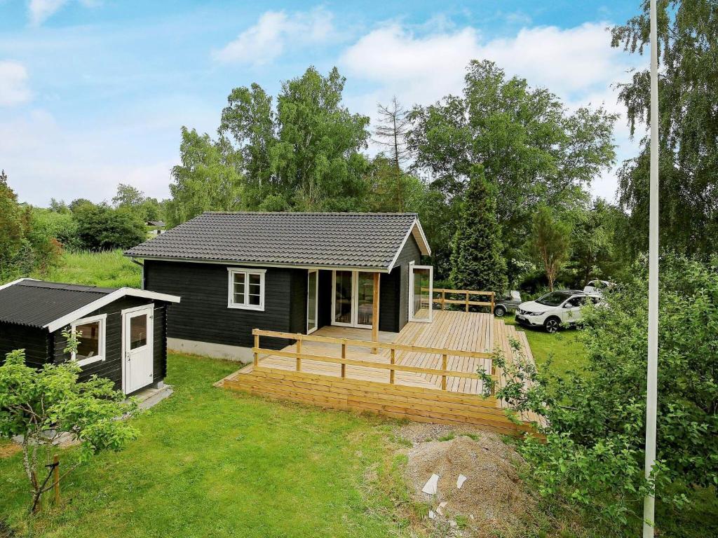 ein kleines Haus mit einer großen Terrasse im Hof in der Unterkunft 4 person holiday home in Skibby in Skibby