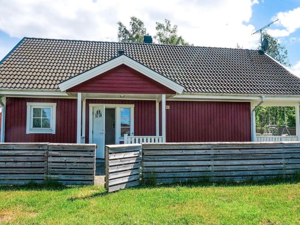 ein rotes Haus mit einem Holzzaun davor in der Unterkunft 6 person holiday home in Unnaryd in Unnaryd
