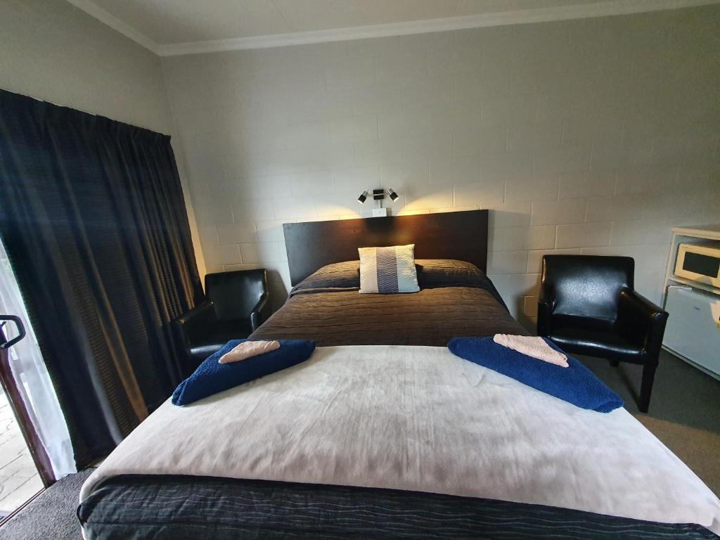 a bedroom with a large bed with two chairs at Matador Motel in Carterton